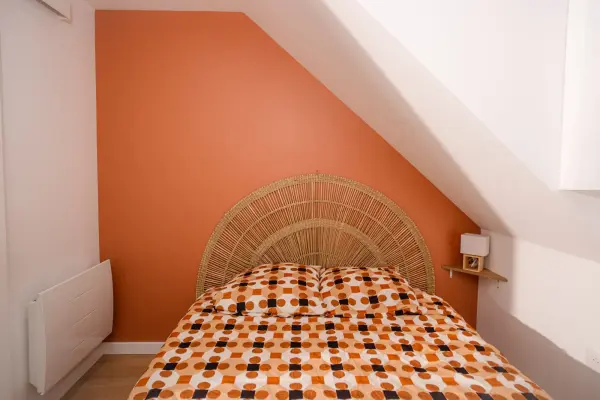 Chambre 1 : vue rapprochée du mur accent orange et de la pente de toit
